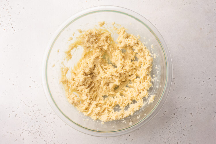 Overhead view of creamed butter and sugar in a large glass mixing bowl.