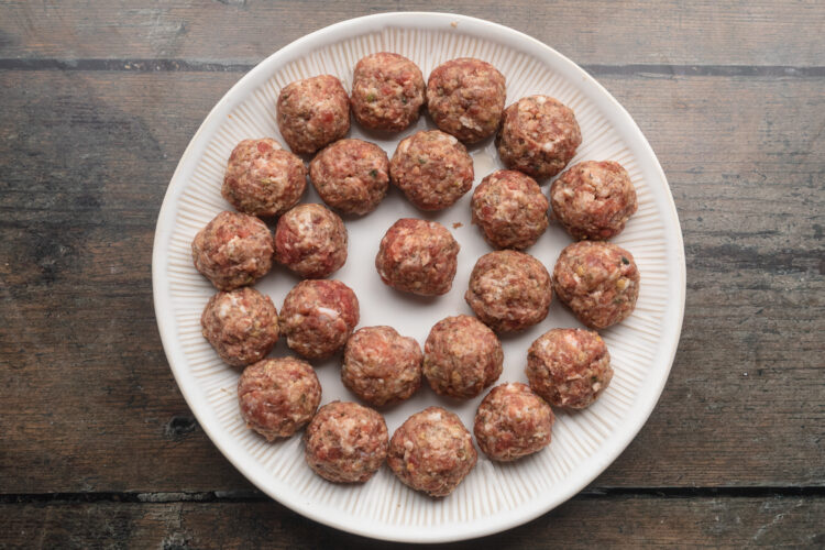 Overhead view of rolled meatballs on a round plate.