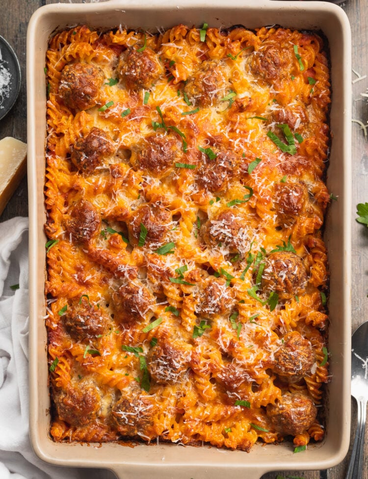 Overhead view of a large pan of meatball casserole with rotini pasta and cheese.