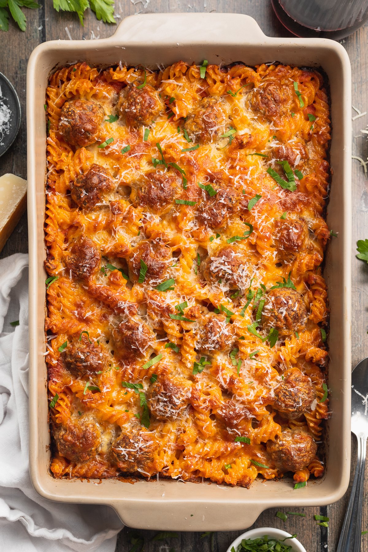 Overhead view of a large pan of meatball casserole with rotini pasta and cheese.