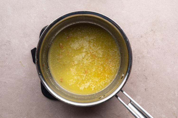 Overhead view of lemon-butter sauce in a silver saucepan.
