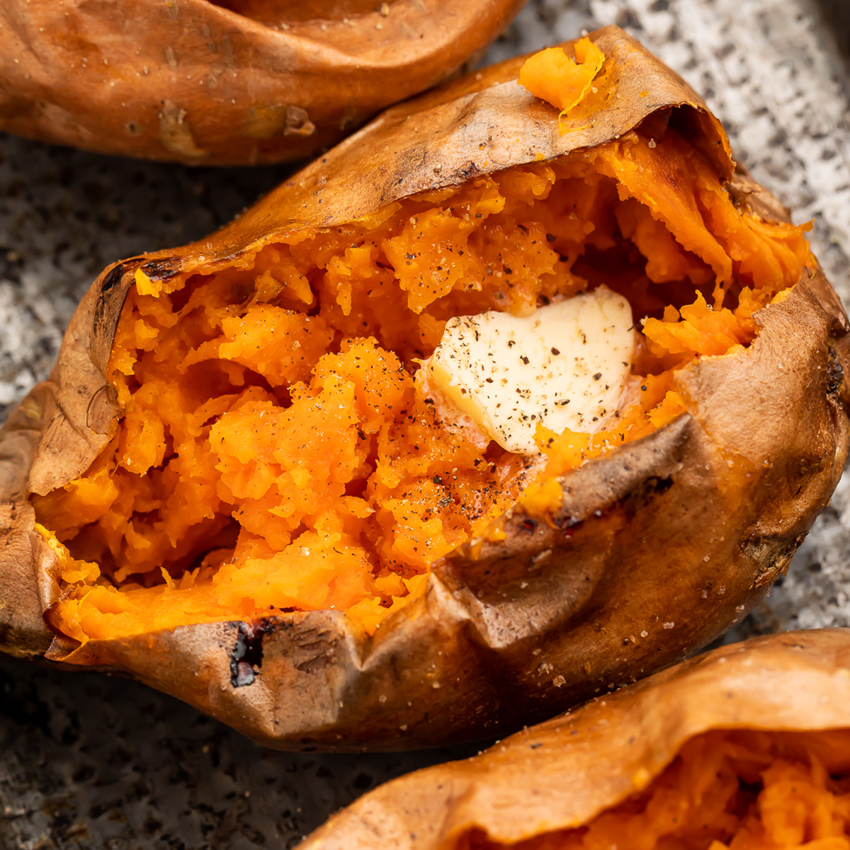 Overhead look at air fryer sweet potatoes topped with butter and pepper.