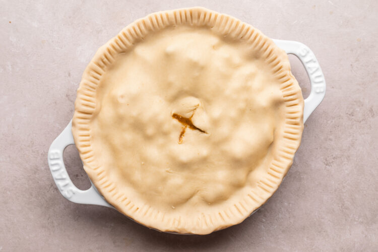 Unbaked beef pot pie in a pie dish with handles.