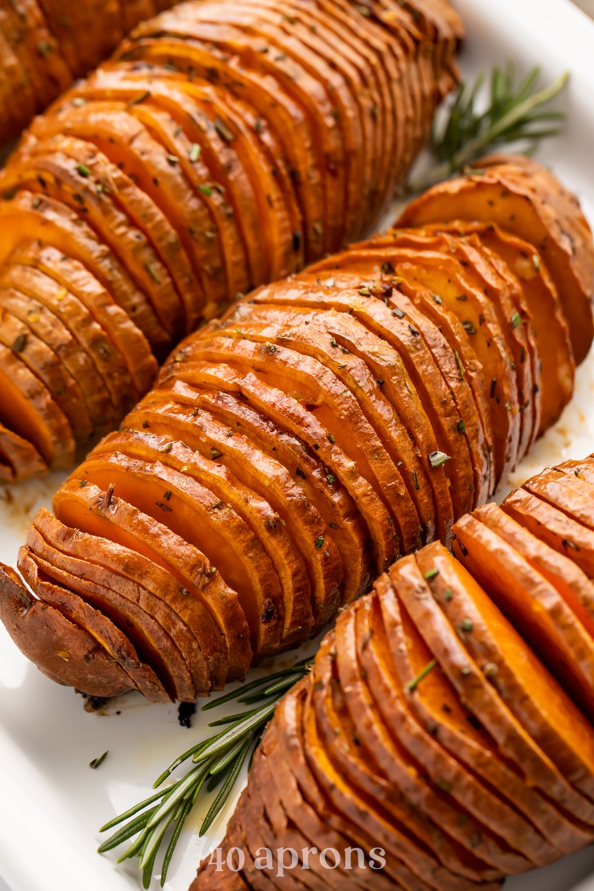 Close-up view of hasselback sweet potatoes on a white tray.