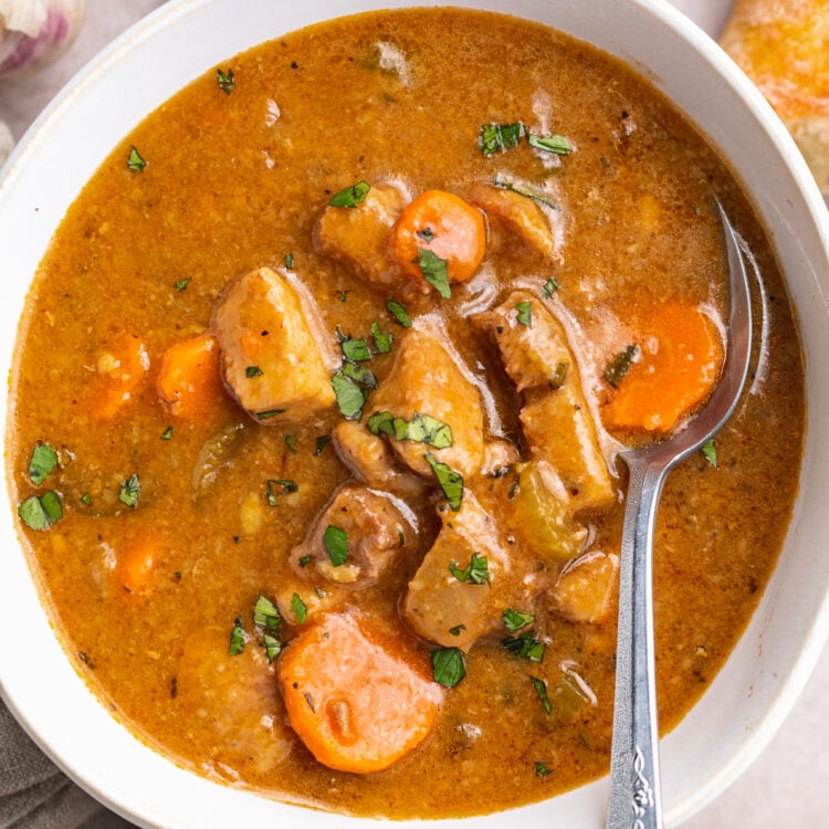 Overhead view of a bowl of pork stew on a table with recipe ingredients scattered around.