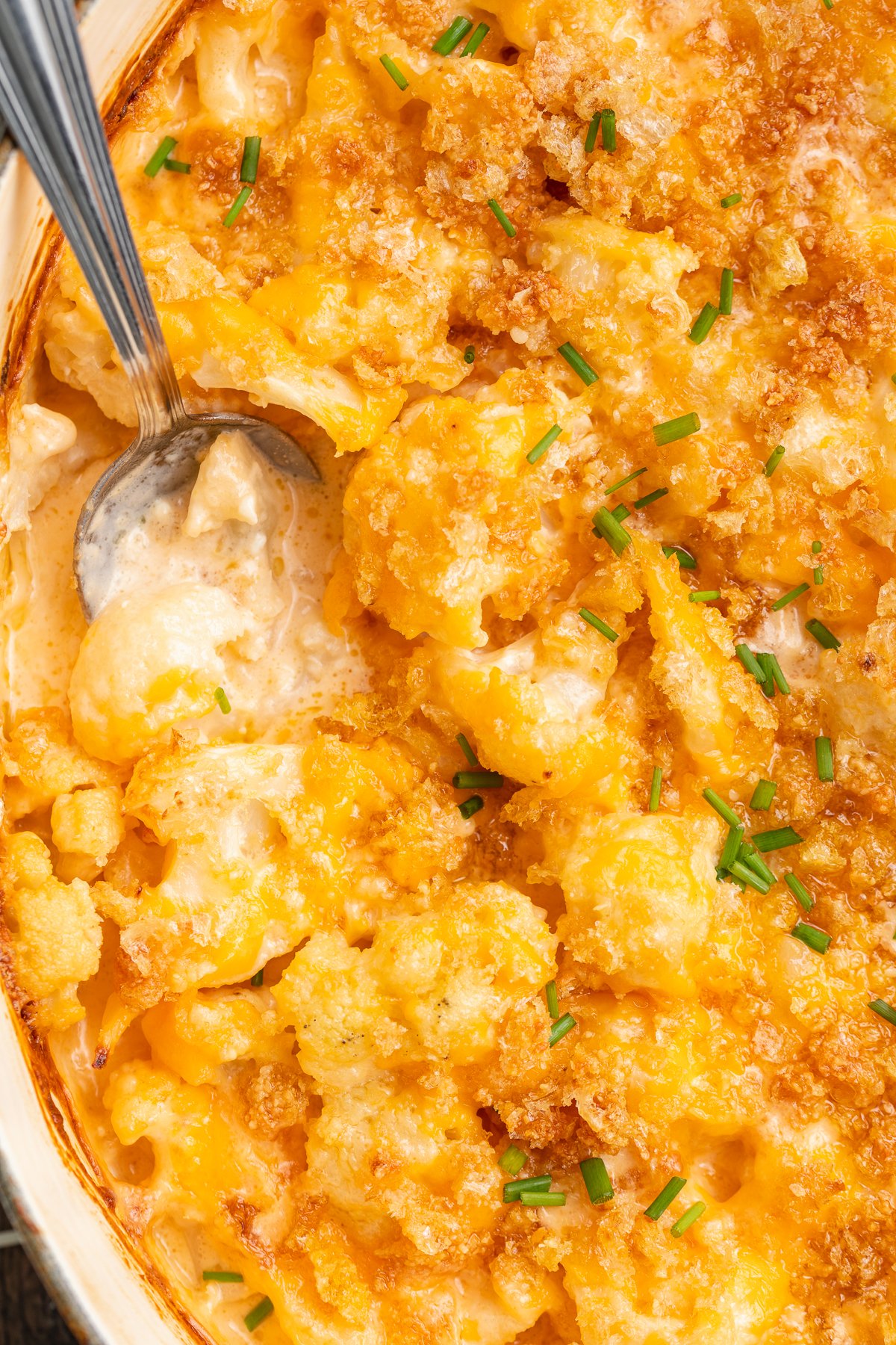 Close-up view of keto mac and cheese in a casserole dish with a large silver spoon.