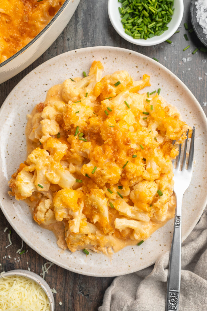 Overhead view of keto mac and cheese plated on a serving plate with a fork on a dark table.