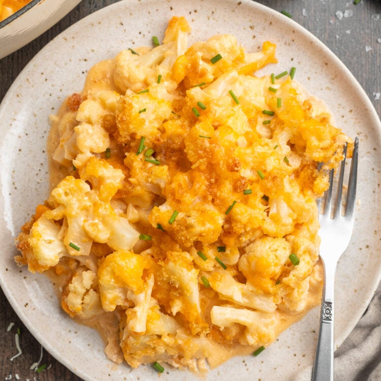 Overhead view of keto mac and cheese plated on a serving plate with a fork on a dark table.