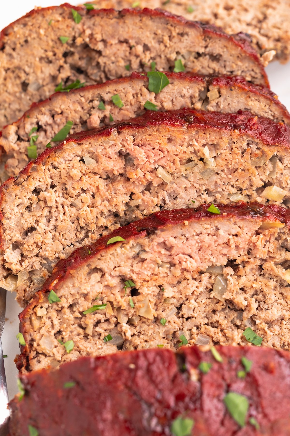 Close-up shot of several slices of Whole30 meatloaf lined up in a staggered line to show edges and centers.