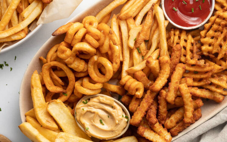 A plate of different types of frozen french fries, cooked in the air fryer.