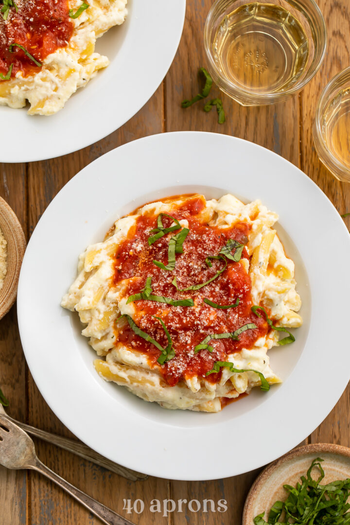 Overhead view of a plate of lemon ricotta pasta with marinara with parmesan and basil.