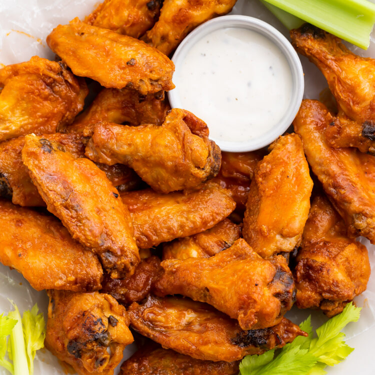 A large plate filled with Whole30 buffalo wings, celery stalks, and a small ramekin of Whole30 ranch dressing.
