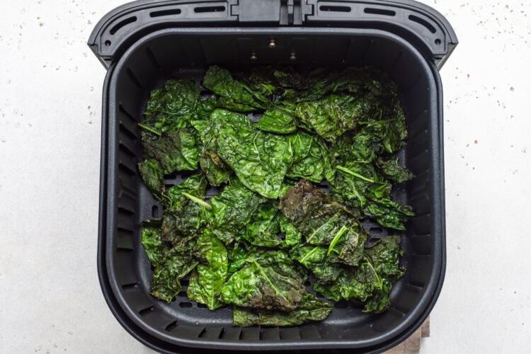 Air fryer kale chips in an air fryer basket.