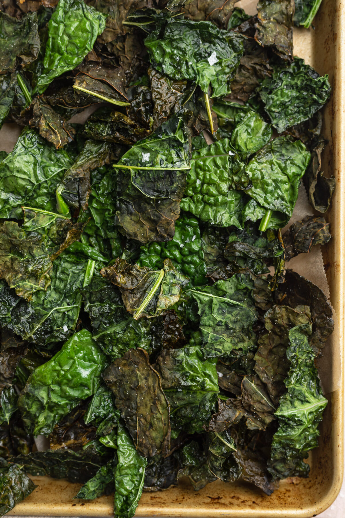 Close-up of deep green, crispy air fryer kale chips on a large baking sheet.