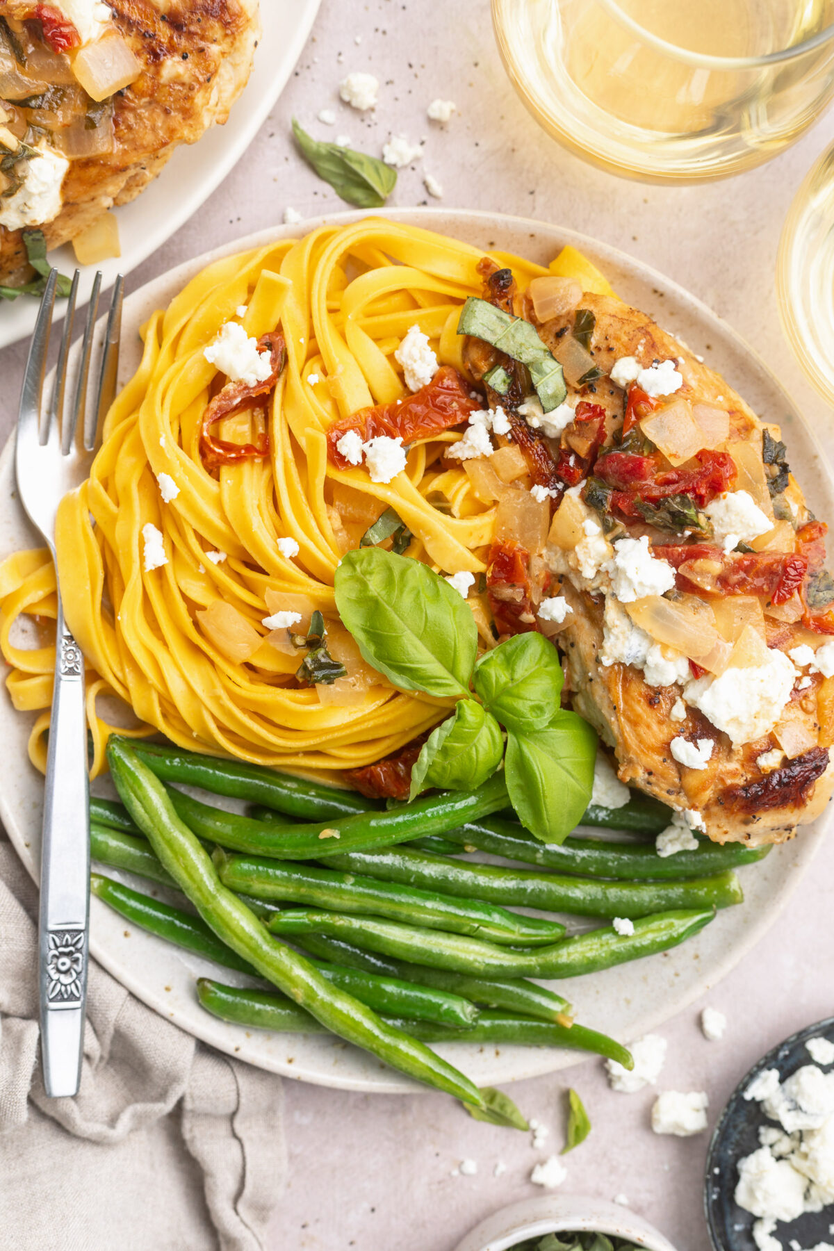 Chicken Bryan plated with swirled pasta and tender green beans, with goat cheese, sun-dried tomatoes, and basil.