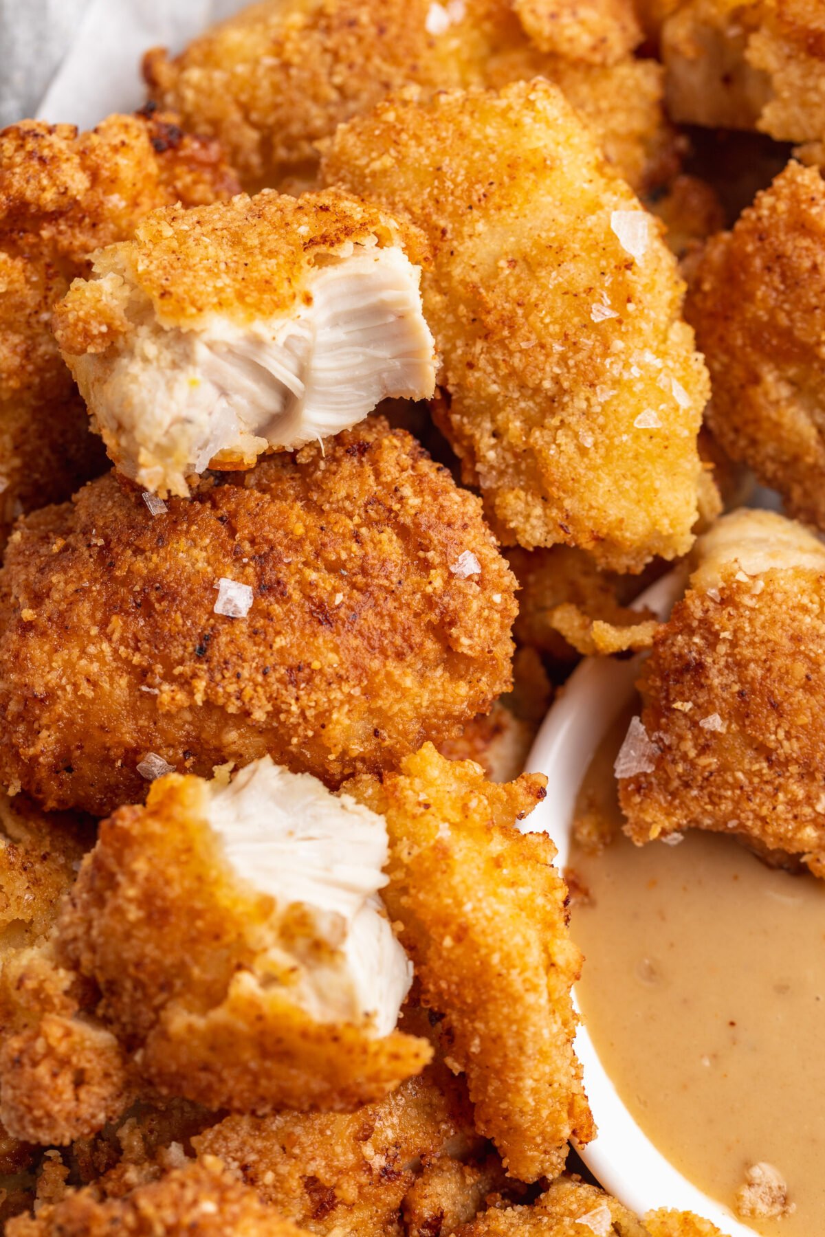 Close up of keto chicken nuggets, with one nugget cut in half to show cross section.