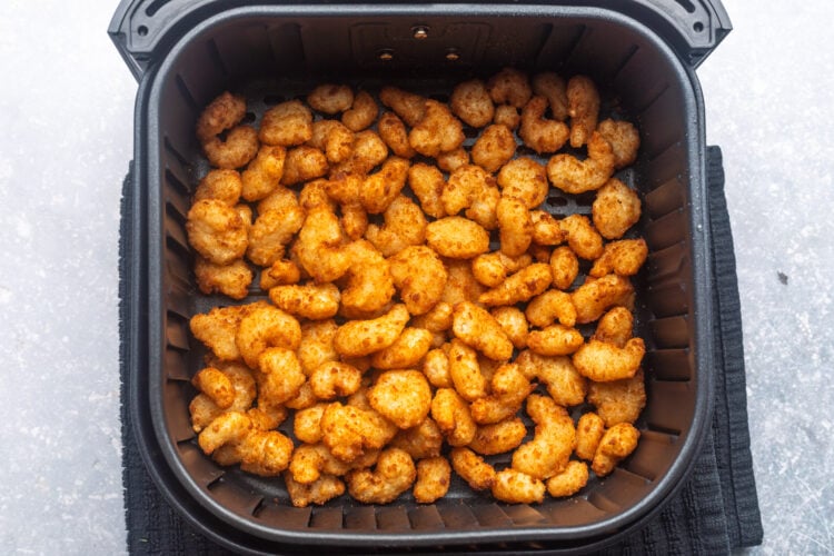 Frozen popcorn shrimp in the air fryer basket, cooked until golden and crispy.