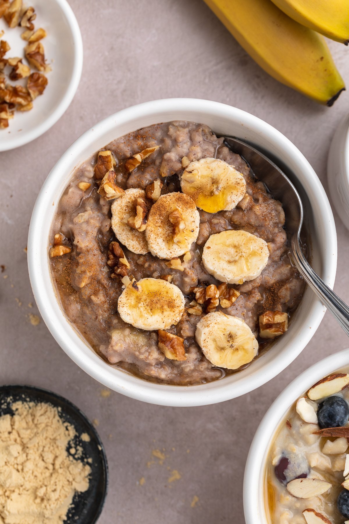 Close-up overhead photo of banana nut protein oatmeal in a small white ramekin with a silver spoon.