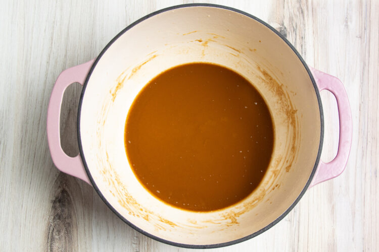 Rich, deep, dark brown roux made from butter and flour in a large heavy-bottomed pot with two handles.