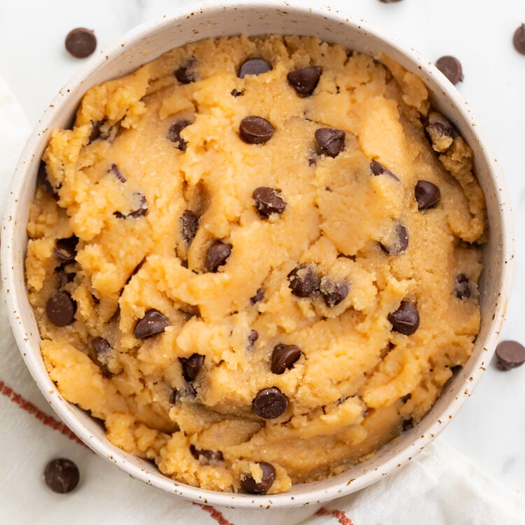 Keto cookie dough in a large bowl with keto chocolate chips sprinkled around the bowl.