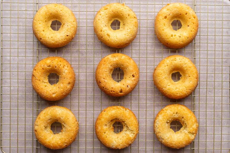 Keto donuts, fully baked and golden, resting on a wire cooling rack as they cool completely.