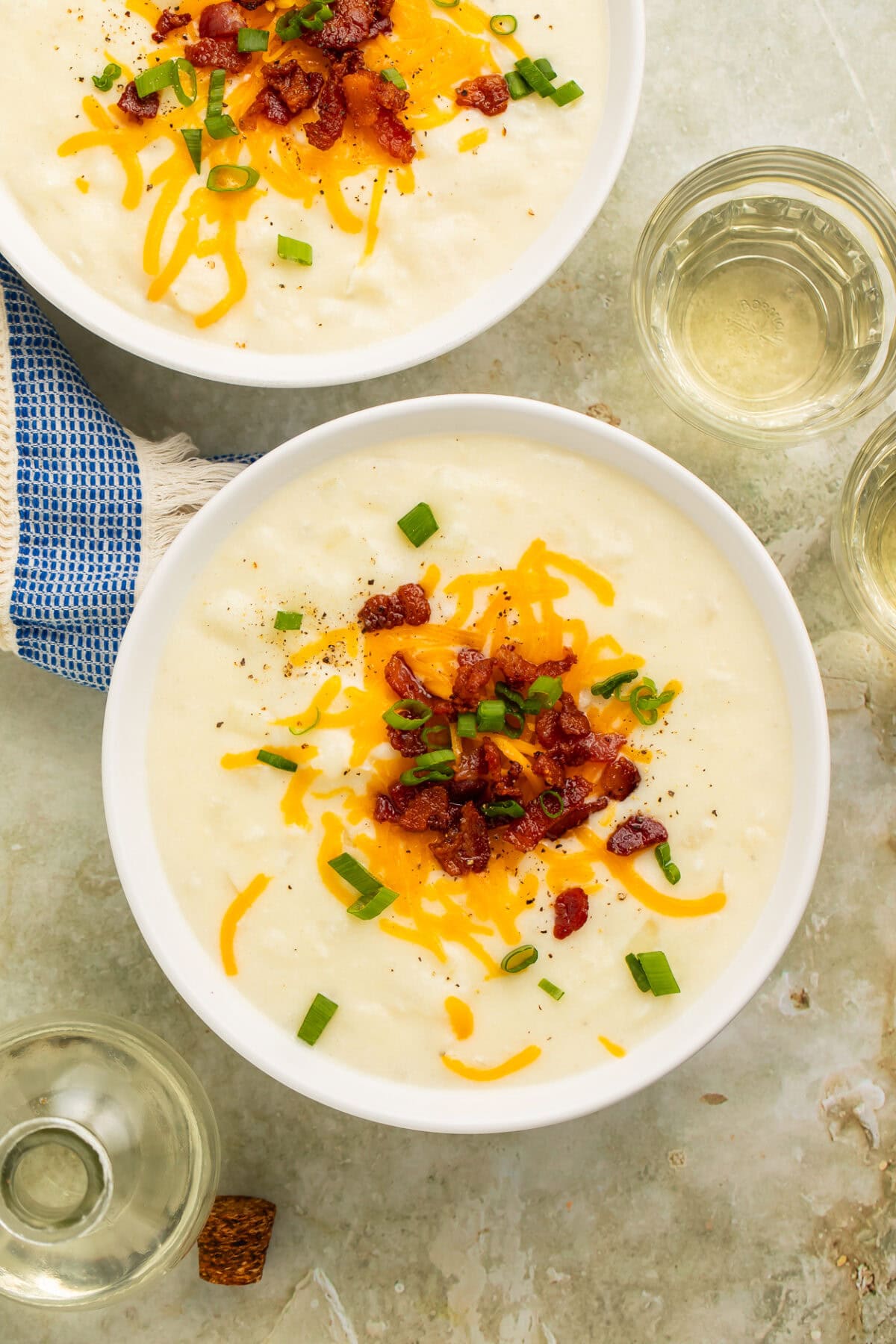 Spoon lifting a bite of loaded potato soup showing creamy texture with melted cheese and bacon.
