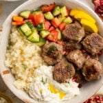 Closeup look at Whole30 gyro meatballs in a bowl in a bowl with cauliflower rice, paleo tzatziki, cucumber and tomato salad, and cauliflower tabbouleh.