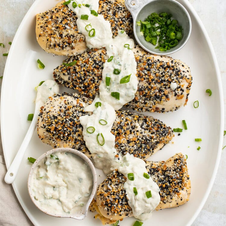 Whole30 Everything Bagel chicken with a dairy-free scallion "cream cheese" sauce on a white oval platter.