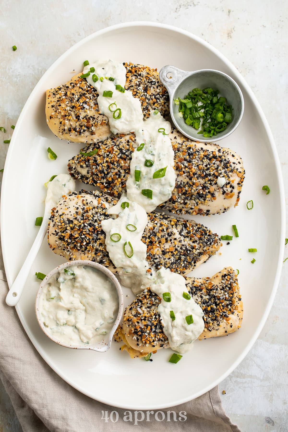 Whole30 Everything Bagel chicken with a dairy-free scallion "cream cheese" sauce on a white oval platter.