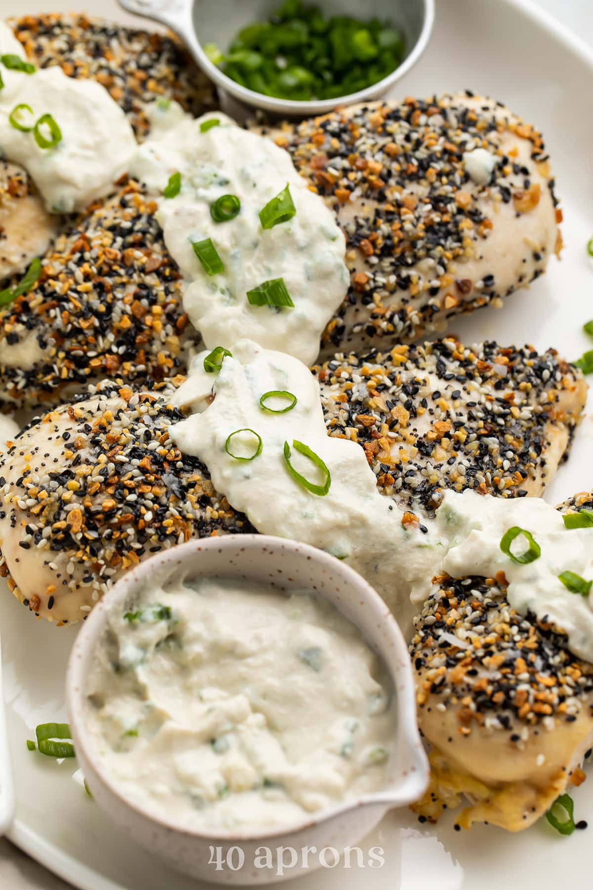 Whole30 Everything Bagel chicken with a dairy-free scallion "cream cheese" sauce on a white oval platter.