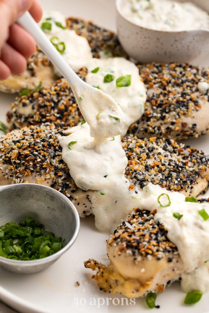 Dairy-free cream cheese sauce being spooned over Whole30 everything bagel chicken.