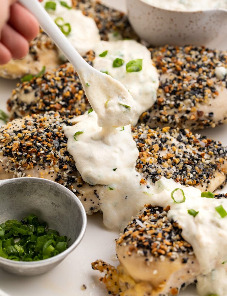 Dairy-free cream cheese sauce being spooned over Whole30 everything bagel chicken.