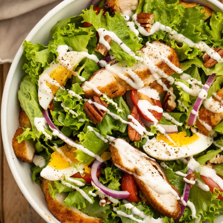 Whole30 southern fried chicken salad with lettuce, fried chicken, red onion, eggs, pecans, and ranch dressing.