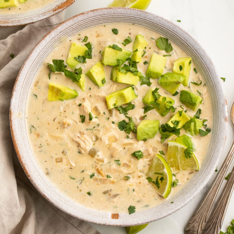 Top-down view of a bowl of Whole30-compliant white chicken chili topped with avocado and cilantro.