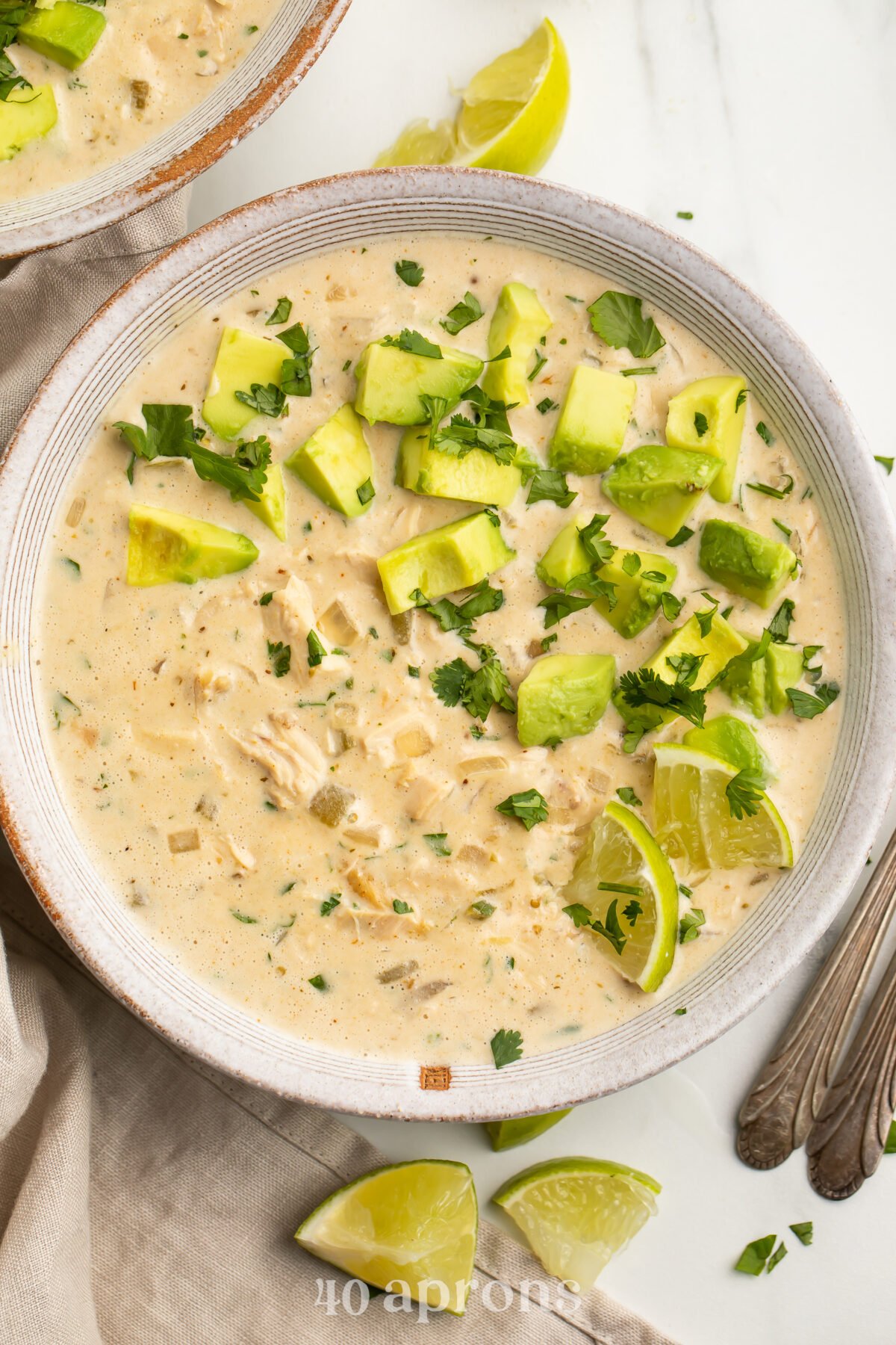 Top-down view of a bowl of Whole30-compliant white chicken chili topped with avocado and cilantro..