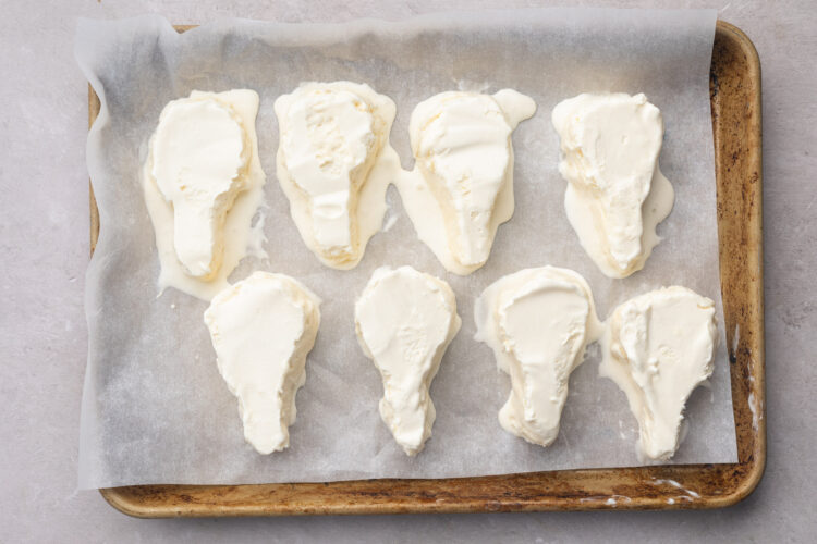 Overhead look at drumstick-shaped ice cream bars lining a baking sheet covered with parchment paper.
