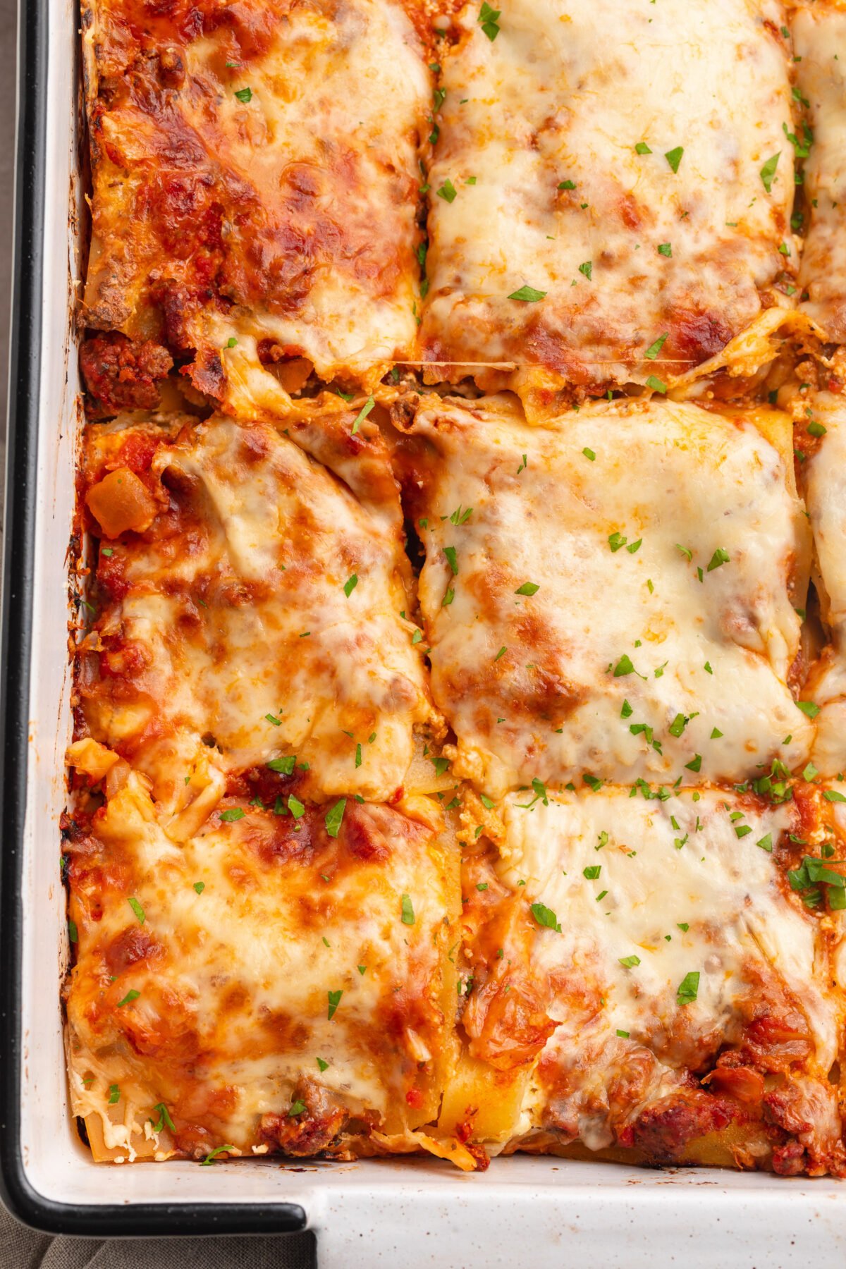 Top-down, overhead view of gluten-free lasagna, sliced into squares, in a baking dish.