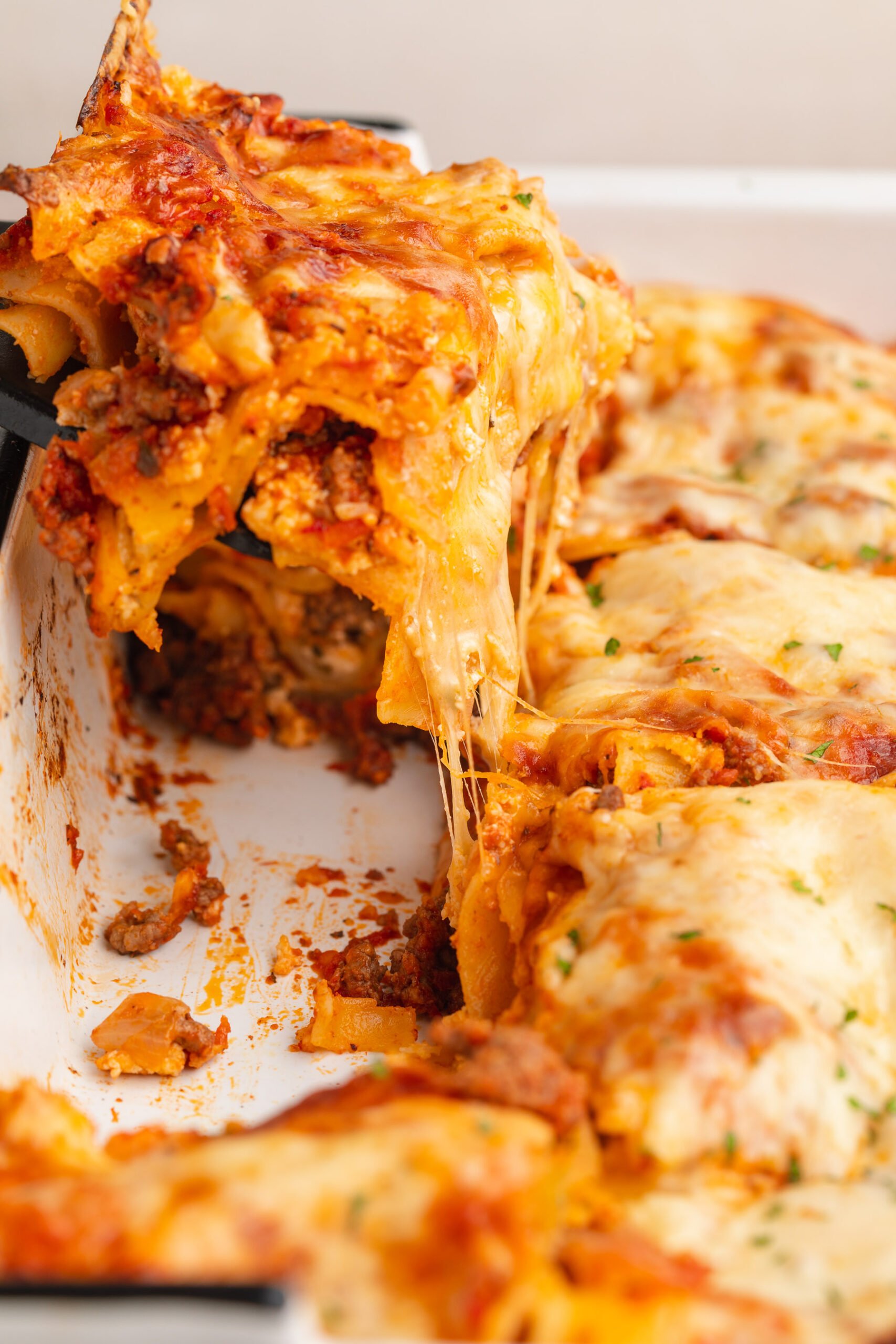 A square of gluten-free lasagna being lifted out of a casserole dish of lasagna.