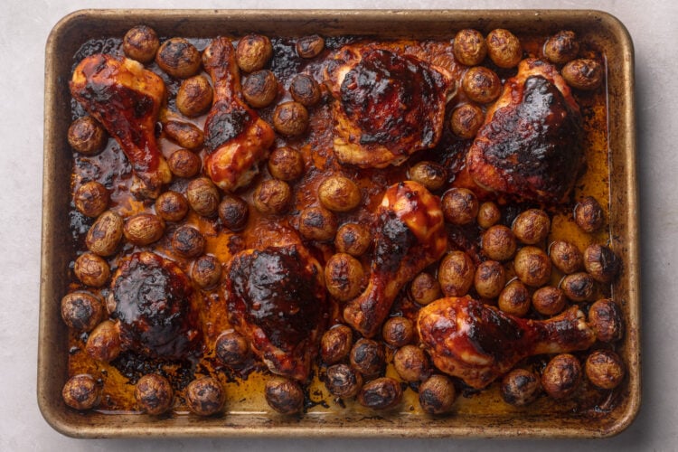 Oven-roasted gochujang chicken thighs and gochujang-coated potatoes on a sheet pan.
