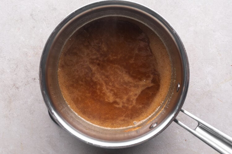Brown swerve and melted butter in a silver saucepan on a neutral countertop.
