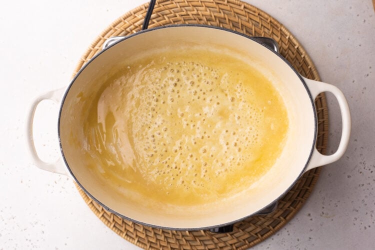 Overhead view of melted butter in a large oval baking dish with two handles.