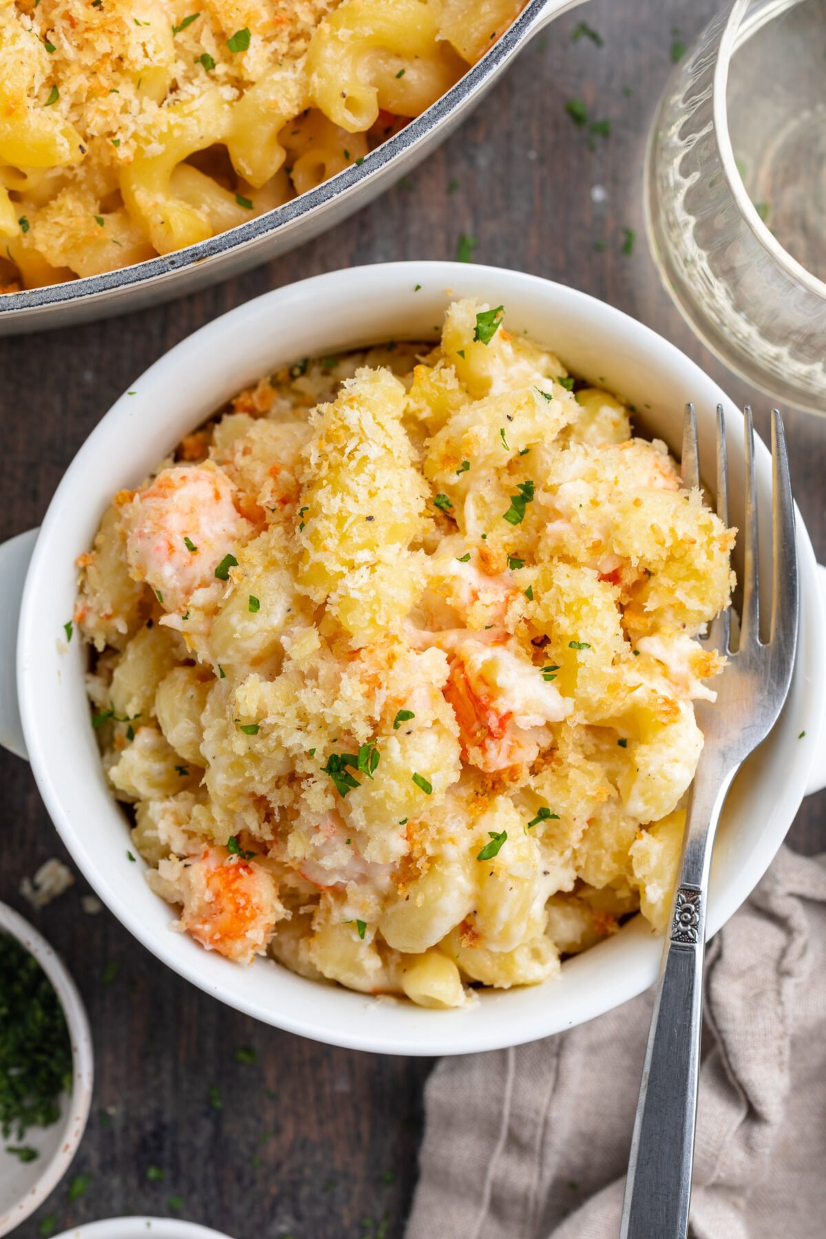 Overhead, top-down view of a small ramekin filled with lobster mac and cheese with a crumb topping.