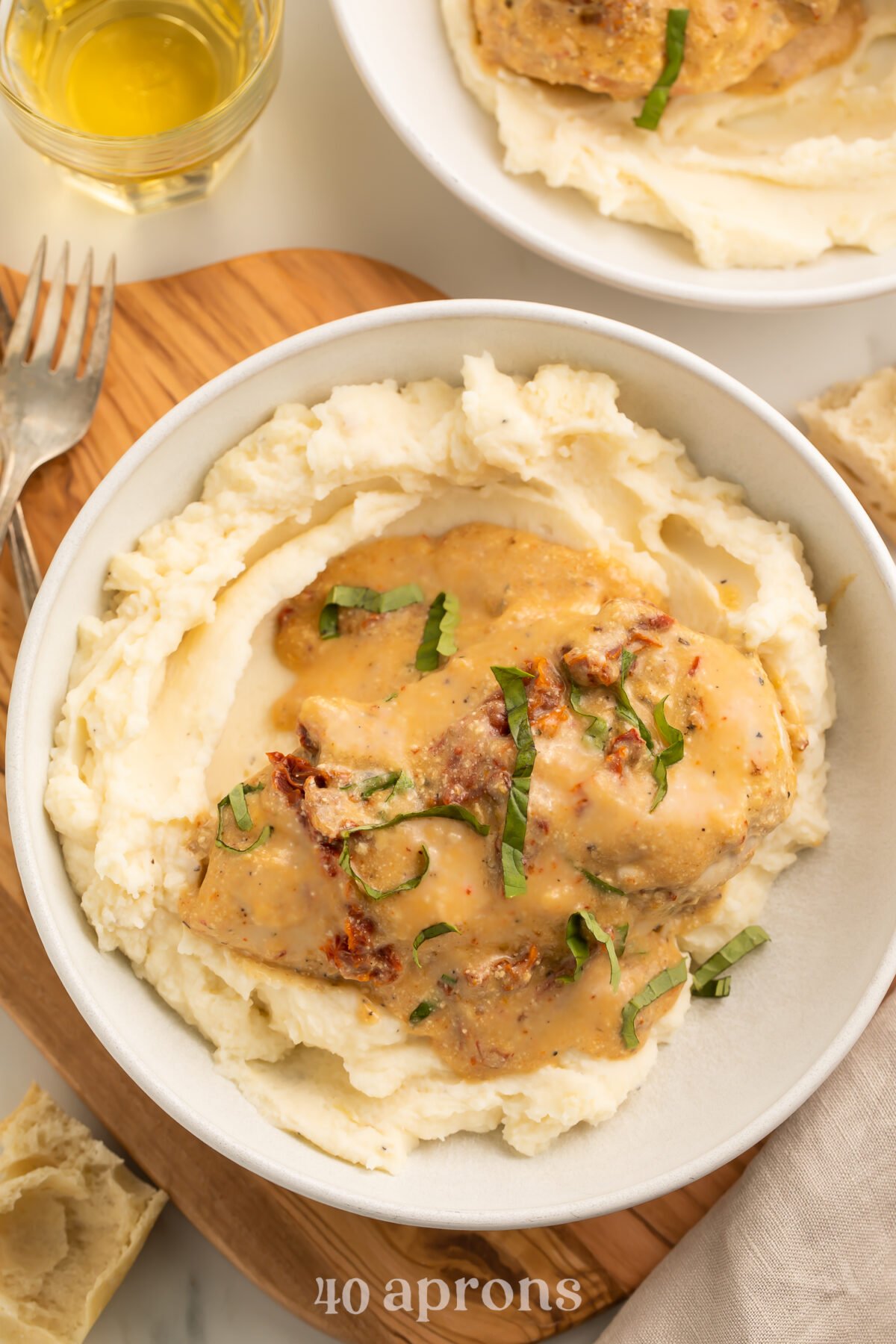 Top-down, overhead view of a Crockpot-cooked marry me chicken breast with sauce atop a bed of mashed potatoes in a large white bowl.