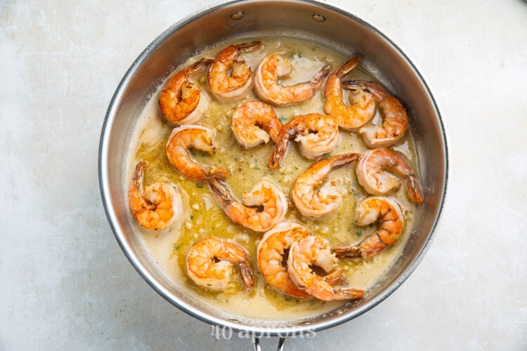 Sauteed shrimp in garlic butter sauce in a silver pan.