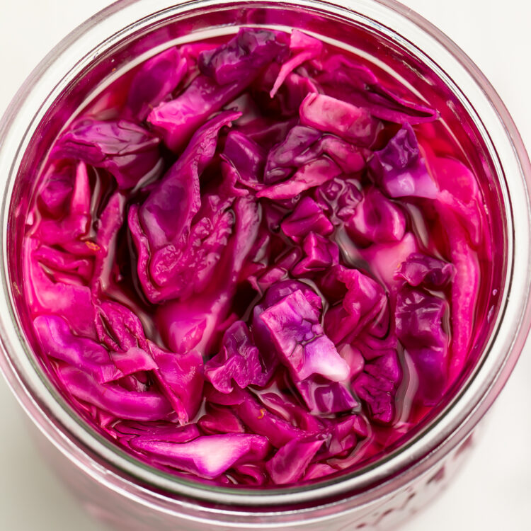 Top down view of pickled red cabbage in a large glass jar.