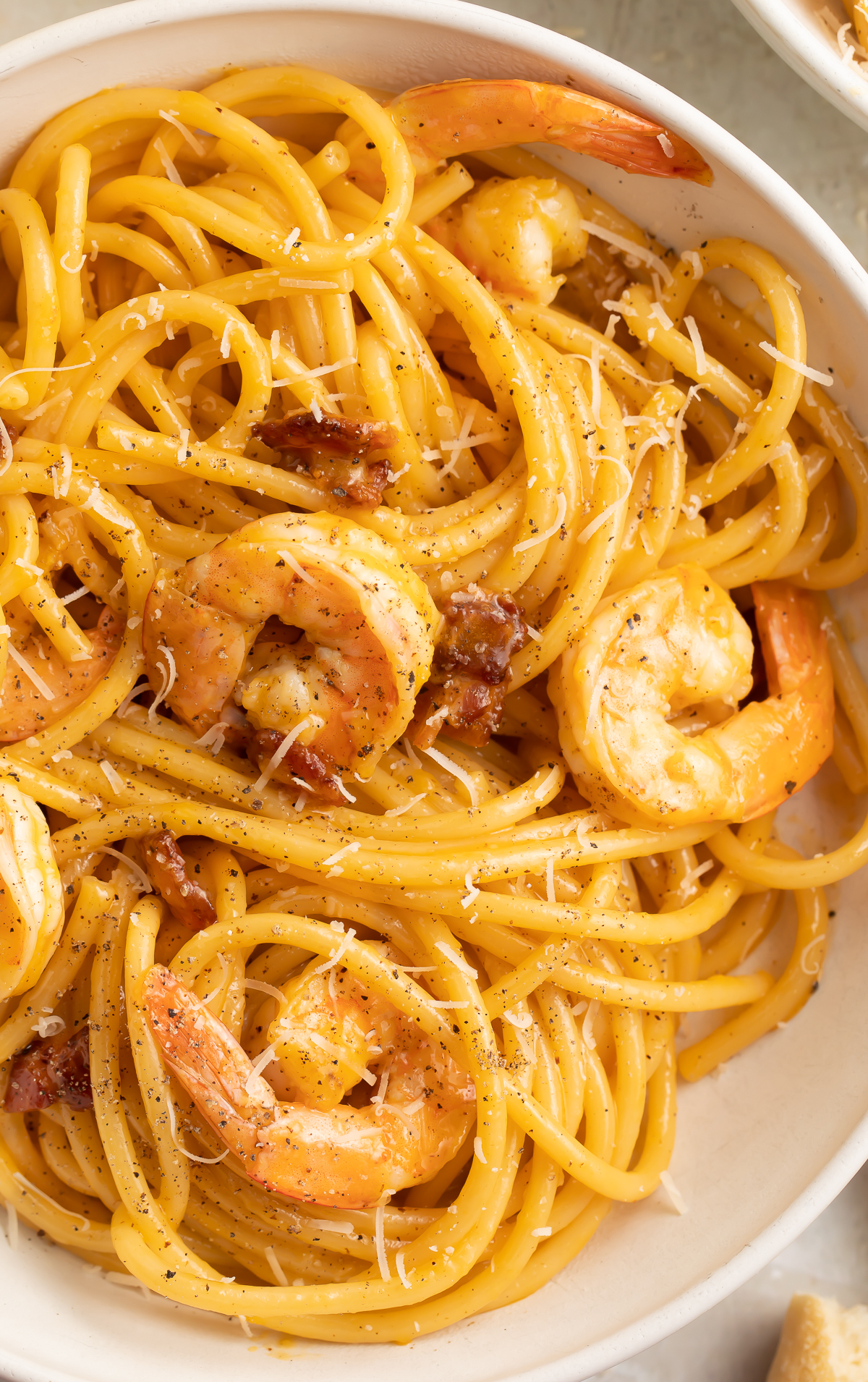 Close-up view of shrimp carbonara in a large white pasta bowl.