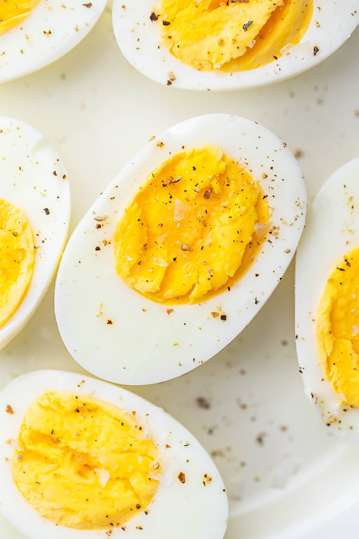 Air fryer hard-boiled eggs, cut in half and seasoned with black pepper, resting on a plate.