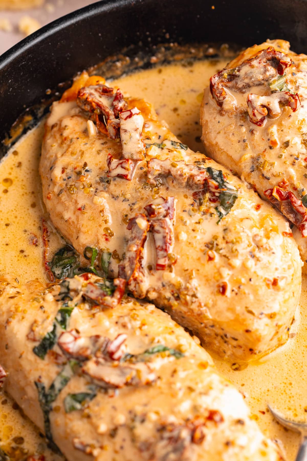 Marry Me Chicken breasts in a cast-iron skillet with basil and sun-dried tomatoes.