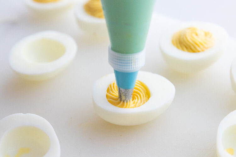 Egg yolk filling being piped directly into empty egg white.