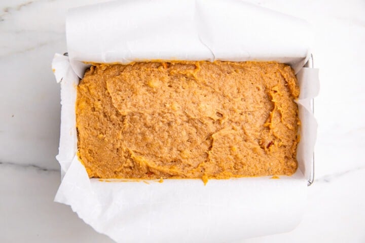 Prepared paleo almond flour banana bread batter in loaf pan lined with parchment paper.